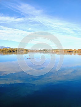 Lake landscape with calm water under blue autumn sky. A view of Beautiful natural lake of Banyoles, in Catalonia, Spain. A