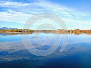Lake landscape with calm water under blue autumn sky. A view of Beautiful natural lake of Banyoles, in Catalonia, Spain. A