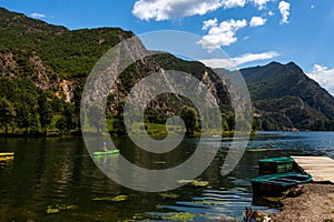 Lake landscape with canoes, kayak, mountains and forest in a sunny summer day with some clouds