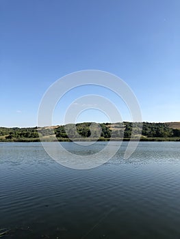 Lake landscape with sky and field with tree