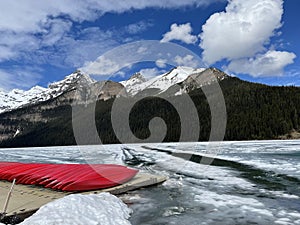 Lake Louise in Banff National Park in late May where it is partially frozen showing the red canoes