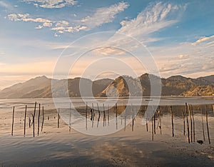 Lake Lut Tawar in Takengon, a serene morning masterpiece: calm waters mirror the dawn's pastel palette.