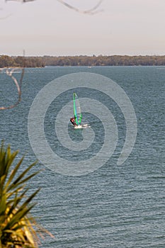 Lake Macquarie, NSW/Australia - December 2018: Mature adult in his fifties speeding into shore on the short board windsurfer,