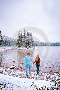 Lake Minnewanka Banff national park Canada, couple walking by the lake during snow storm in October in the Canadian