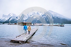 Lake Minnewanka Banff national park Canada, couple walking by the lake during snow storm in October in the Canadian