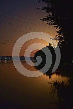 Lake at night reflecting shiny moon on water surface