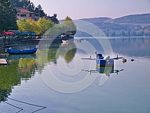 Lake Orestiada, Kastoria Greece. Reflections of boat, land and houses on calm water