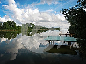 Lake Pier with sky and clouds reflecting in tranquil River