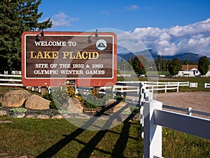 Lake Placid, New York, welcome sign in sunshine and with mountains in the backdrop.