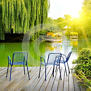 Lake, pleasure boats and garden furniture on wooden pier
