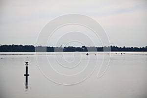 Lake with a pole in the distance on a cloudy day