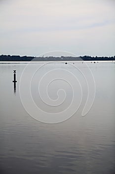 Lake with a pole in the distance on a cloudy day