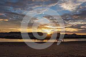 Lake Powell - Silhouette of woman walking with her dog along the shoreline of Lake Powell on Lone Rock Beach in Wahweap,