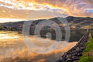 Lake with promenade, sunset sky reflection and foothills. Snake River on the border of Idaho and Washington states.