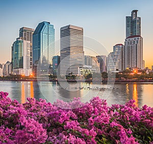 Lake with Purple Flowers in City Park under Skyscrapers at Sunrise