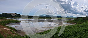 Lake with reflection of the sky and steamy hotsprings in Uzon Caldera