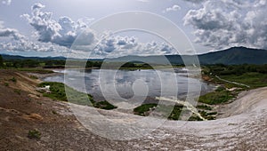 Lake with reflection of the sky and steamy hotsprings in Uzon Caldera