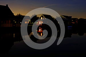 Lake resort scene at dusk with lights on in homes