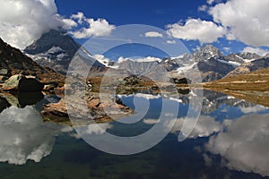 The lake Riffelsee, mountains and clouds reflected in it, on a mountain Gornergrat, near Zermatt, in southern Switzerland