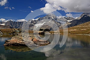 The lake Riffelsee, mountains and clouds reflected in it on a mountain Gornergrat, near Zermatt, in southern Switzerland