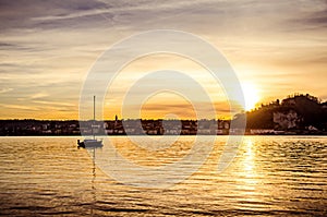 Lake with sail yacht and city in the sunset. Lago Maggiore and Arona