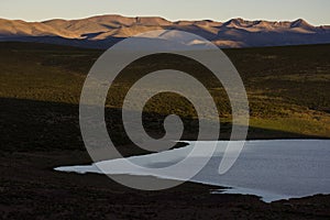 Lake shore at late afternoon with sun over the background mountains in Jujuy, Argentina