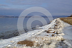 Lake shore with a strip of snow and ice