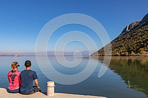 Lake Skadar - Couple sitting on pier with panoramic view of Lake Skadar National Park in autumn seen from Godinje, Bar, Montenegro