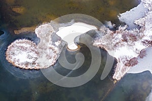 Lake with a small island and shore area - winter scenery - with a bizarre ice structure on a water surface and snow-covered shore
