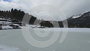 Lake Spitzingsee in winter covered with snow and ice in freezing cloudy weather in Bavaria, Germany. A mountain lake in