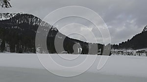 Lake Spitzingsee in winter covered with snow and ice in freezing cloudy weather in Bavaria, Germany. A mountain lake in