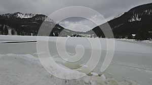 Lake Spitzingsee in winter covered with snow and ice in freezing cloudy weather in Bavaria, Germany. A mountain lake in