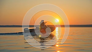 Lake in sunlight is getting crossed by two fishermen