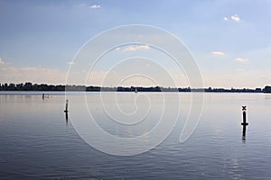 Lake at sunset with the sky casted in the water and a sailboat in the distance