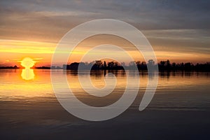 Lake at sunset with the sky casted in the water seen from the shore