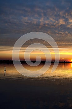 Lake at sunset with the sky casted in the water seen from the shore