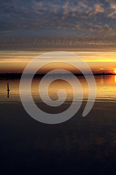 Lake at sunset with the sky casted in the water seen from the shore