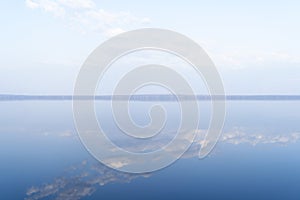 Lake surface with calm water. Smooth water surface with cloud reflections and horizon line. Still calm water texture background.