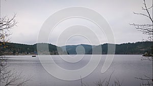 Lake surrounded by green trees and mountains in fall, time lapse