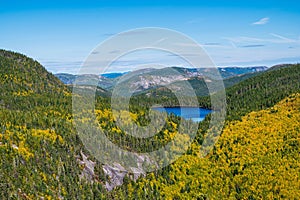 Lake surrounded by hills and trees covered in colorful leaves in Grands-Jardins national park