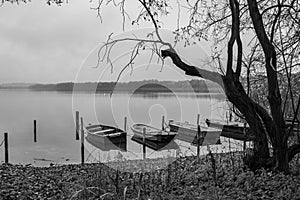 a lake there are several rowing boats on the shore and they are chained and the water is mirror-smooth