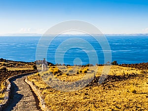 lake Titicaca at sunset, with a local farmer riding down to the village through a stone path, Amantani island, Peru