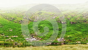 Lake under hill in fog, Carpathian mountains, nature landscape.