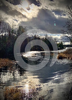 Lake view with dark forbidding clouds and reflecting of the sun in water