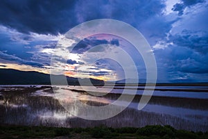 Lake view floating house boat of fishing village at sunset with cloud, rain and storm.