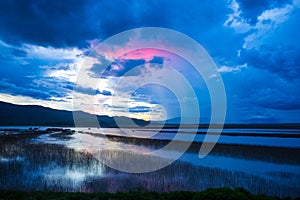 Lake view floating house boat of fishing village at sunset with cloud, rain and storm.