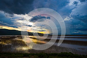 Lake view floating house boat of fishing village at sunset with cloud, rain and storm.