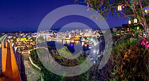 The lake Voulismeni in Agios Nikolaos at night with fullmoon, a picturesque coastal town with colorful buildings around the port.