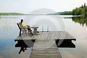 Lake with wooden platform and woman resting.