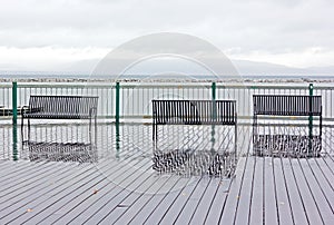 Lakefront benches with reflection on a rainy day in Burlington, Vermont, USA.